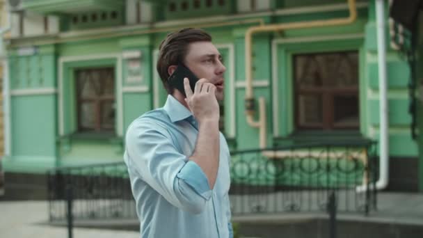 Üzletember, aki mobiltelefonnal sétál a City Streeten. Komoly férfi beszél telefonon. — Stock videók