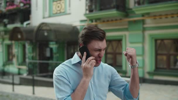 Щасливий бізнесмен святкує перемогу з мобільним телефоном на вулиці — стокове відео