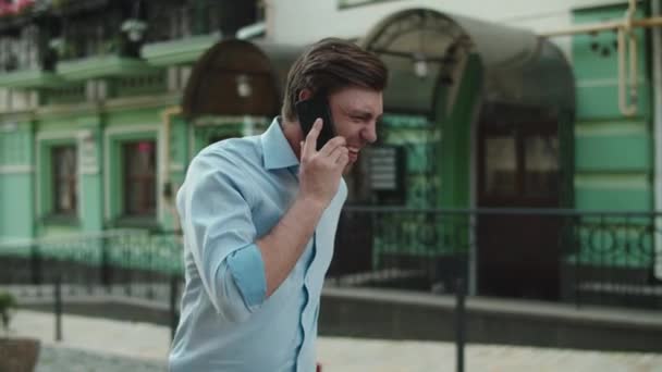 Spännande man dansar med telefon på gatan. Glad affärsman firar segern — Stockvideo