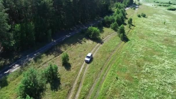 Samochód z widokiem na helikopter jadący przez las. Jazda samochodem przejeżdżającym przez pola — Wideo stockowe