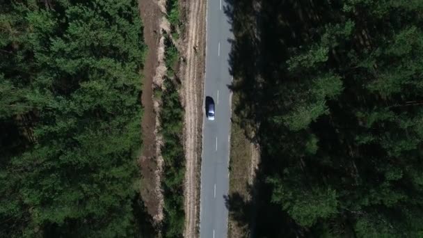 Samochód z widokiem na helikopter jadący na wieś. Dron przelatujący nad samochodem nad lasem — Wideo stockowe