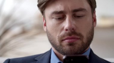 Yakın plan odaklı adam, ofisteki akıllı telefondan mesaj okuyor..
