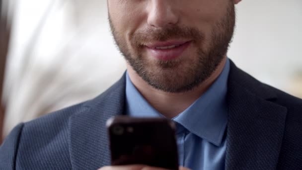 Un homme d'affaires séduisant qui envoie des textos sur son portable. Homme souriant textos sur smartphone. — Video
