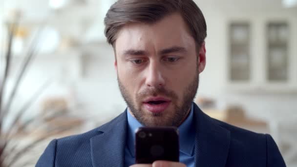 Geschockter Geschäftsmann liest traurige Nachrichten auf seinem Handy. Verblüffter Mann schaut aufs Handy. — Stockvideo