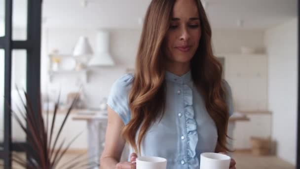 Mujer feliz trayendo tazas de té a su marido en casa. Pareja tomando café — Vídeos de Stock