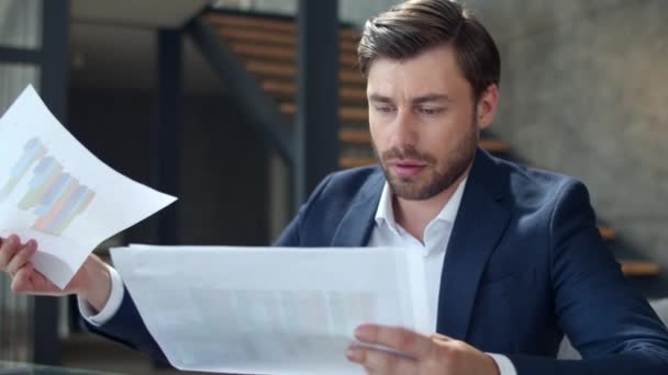 Серьезный бизнесмен смотрит на диаграмму в офисе. Окаменелый человек, читающий документы. — стоковое видео