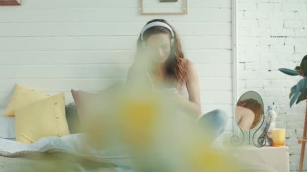 Smiling pregnant woman listening music in bed. Expectant mother resting indoors — Stok video