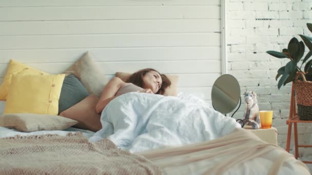 Mooie vrouw die wakker wordt in de slaapkamer. jonge vrouw liggend bed ochtend. — Stockvideo