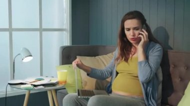 Closeup sad pregnant businesswoman talking phone at home office.