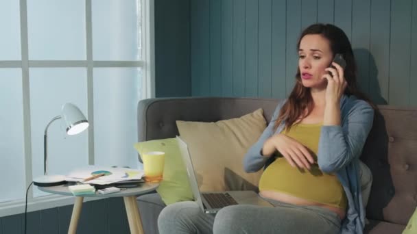 Closeup serious pregnant woman talking mobile phone at home office — Stock Video