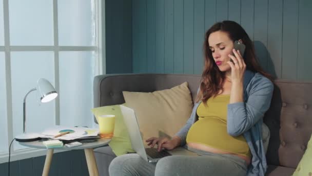 Серьёзная беременная деловая женщина разговаривает по мобильному телефону в домашнем офисе . — стоковое видео