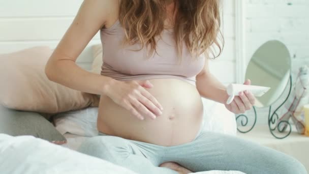 Neznámá těhotná žena carring břicho se smetanou doma. — Stock video