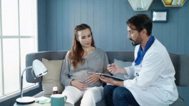 Doğum öncesi kliniğinde doktor tavsiyelerini dinleyen odaklanmış hamile bir kadın..