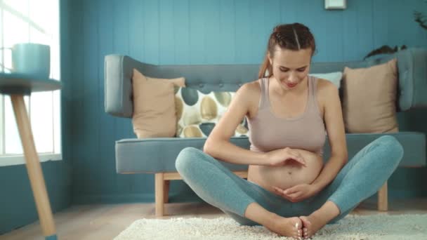 Feliz futura madre mirando a la cámara interior. Madre embarazada sosteniendo el vientre — Vídeos de Stock