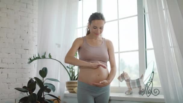 Detailní úsměv břicho matka přemýšlet o budoucí dítě v blízkosti okna doma. — Stock video