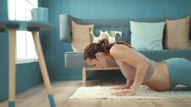 Close-up vrolijke zwangere buik moeder doet yoga oefening in de woonkamer. — Stockvideo