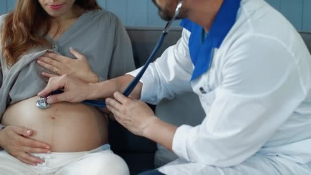 Retrato de obstetra escuchando vientre de futura madre con estetoscopio — Vídeos de Stock