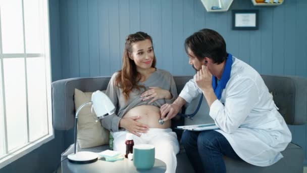 Крупним планом лікар, який вивчає живіт вагітної жінки в пренатальному кабінеті . — стокове відео