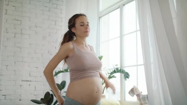 Привлекательная будущая мама делает утренние упражнения у окна дома — стоковое видео