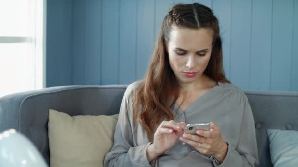 Porträt einer schönen Frau, die zu Hause in Zeitlupe im Smartphone SMS schreibt.