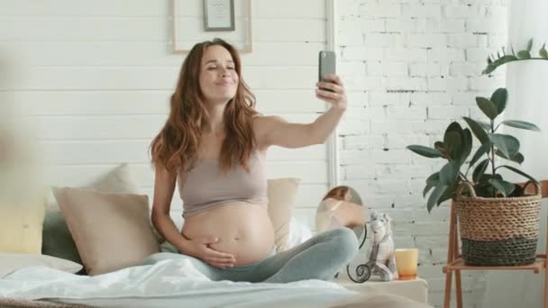 Closeup verwachten moeder het nemen van telefoon selfie haar buik in bed. — Stockvideo