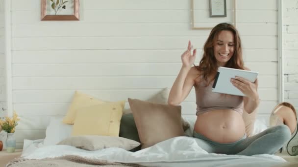 Gravid kvinna säger hej under videosamtal Förväntad mamma chattar hemma. — Stockvideo