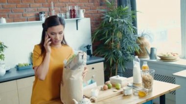 Ev hanımı alışveriş torbalarıyla eve geliyor. Mutfakta telefonla konuşan genç kız..