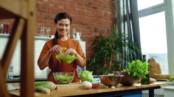 Femme préparant la salade dans la cuisine. Souriante fille déchirant laitue sur saladier . — Video