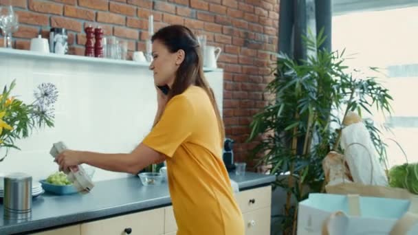 Μια γυναίκα ξεπακετάρει τσάντες στην κουζίνα. Η νοικοκυρά έρχεται σπίτι μετά τα ψώνια.. — Αρχείο Βίντεο