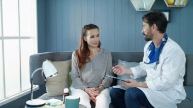 Beautiful pregnant woman talking with doctor on couch in cabinet.