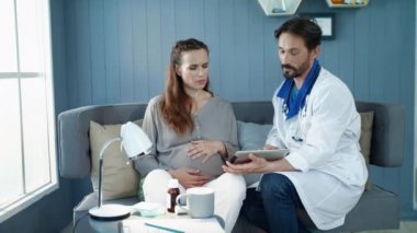 Closeup doctor showing test results in office. Pregnant woman looking tablet