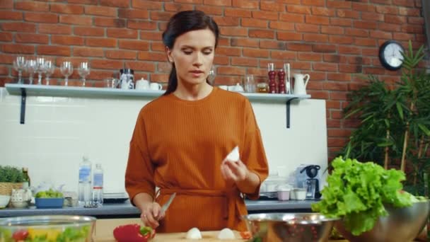 Женщина пробует нарезанную луковую лампочку. Улыбающаяся домохозяйка готовит овощи . — стоковое видео