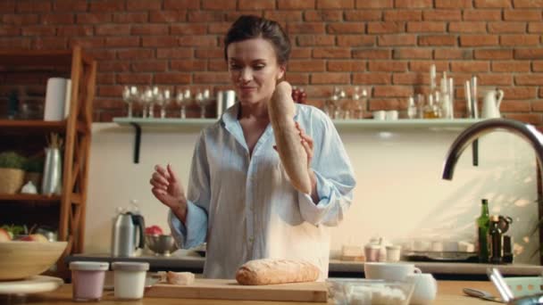 Genç bir kadın tahtadan ekmek kesiyor. Kız evde kahvaltı hazırlıyor.. — Stok video
