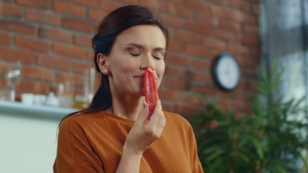 Vrouw die een stuk rode paprika proeft. Meisje ruikt stuk paprika thuis. — Stockvideo