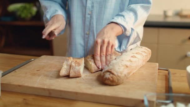 Woman hands slicing bread. Brunette female eating baguette in kitchen. — Stock Video