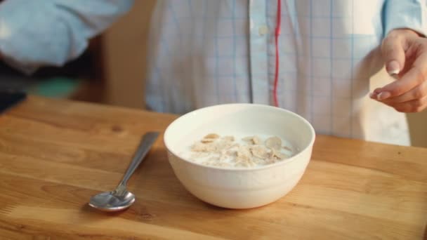 Mulher mãos derramando leite em tigela de flocos de milho. Mulher comendo cereais em casa . — Vídeo de Stock