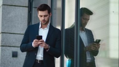Closeup man standing with phone outside. Businessman using smartphone at street
