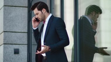 Closeup man arguing by phone at street. Businessman talking phone near building