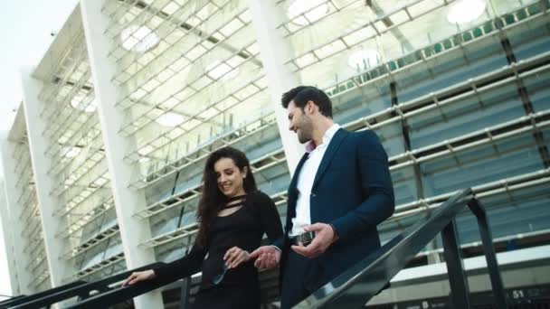 Vue de côté homme d'affaires et femme souriant dehors. Couple marchant en bas — Video