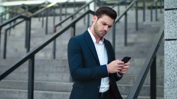 Mężczyzna z bliska piszący przez telefon na zewnątrz przy schodach. Mężczyzna korzystający z telefonu komórkowego na zewnątrz — Wideo stockowe