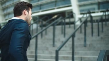 Portrait businessman walking upstairs near stadium. Man looking away outdoors