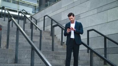 Modern caddede telefonu kullanan bir adam. İş adamı dışarıdaki saati kontrol ediyor.