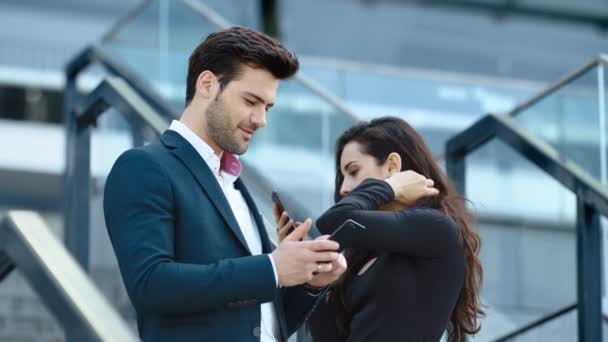 Coppia di primi piani utilizzando i telefoni in strada. Coworkers parlando insieme in strada — Video Stock