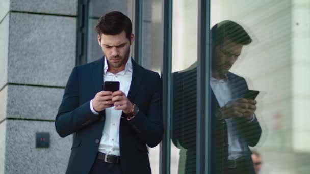 Un hombre de negocios cercano parado cerca del edificio. Empresario usando teléfono inteligente fuera — Vídeo de stock