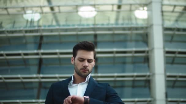 Um empresário próximo a descer as escadas. Homem verificando o tempo no relógio de pulso — Vídeo de Stock