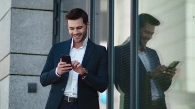 Closeup man standing in black suit at street. Businessman using smartphone