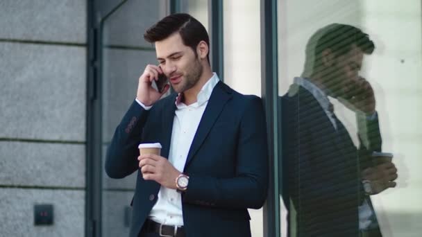 Closeup businessman standing at street. Man smiling with phone in suit outside — Stockvideo