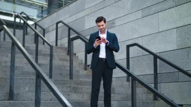 Dışarıdaki merdivenlerde telefonu kullanan bir iş adamı. İşadamı merdivenlerde gülümsüyor.