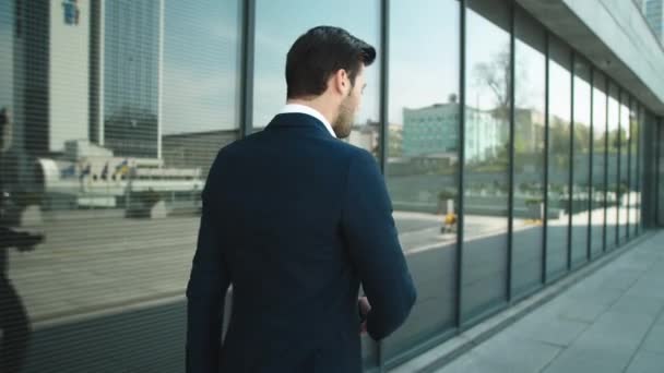 Achteraanzicht zakenman loopt met telefoon. Man met smartphone buiten — Stockvideo