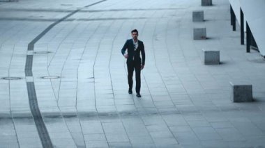 Sokakta şık takım elbiseli bir adam yürüyor. İş adamı kağıtları dışarı atıyor.